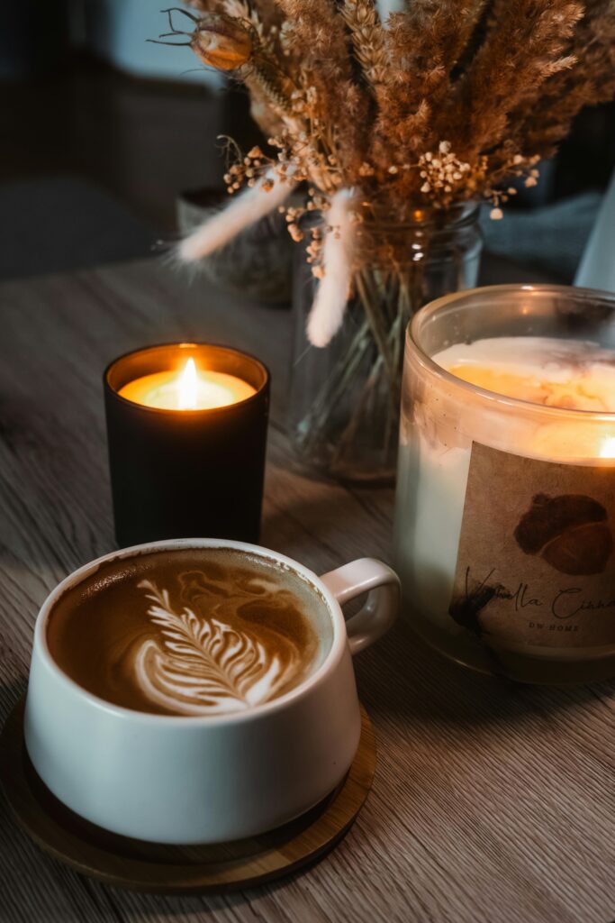 Warm latte art alongside flickering candles and dried florals for a relaxing ambiance.