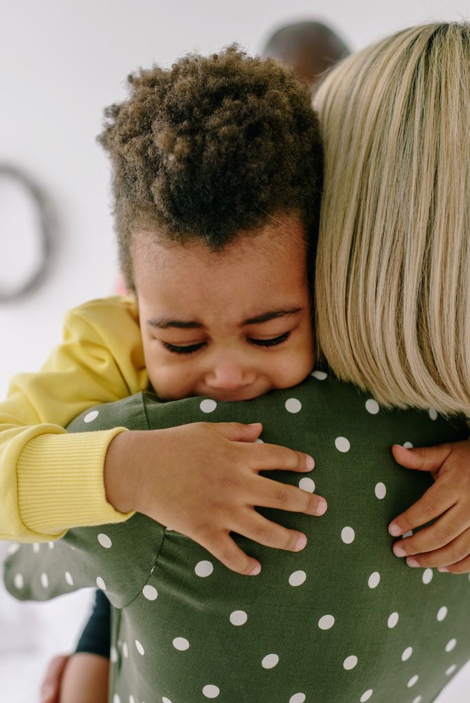 A caring mother comforts her crying child in a close embrace, showcasing love and support.