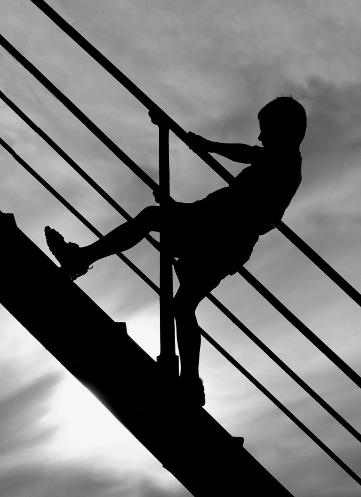 A silhouette of a child climbing stairs against a dramatic sunset sky, creating a moody atmosphere.