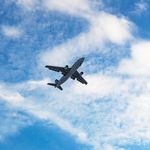 A commercial airplane flying high in the clear blue sky with fluffy clouds in Turkey.