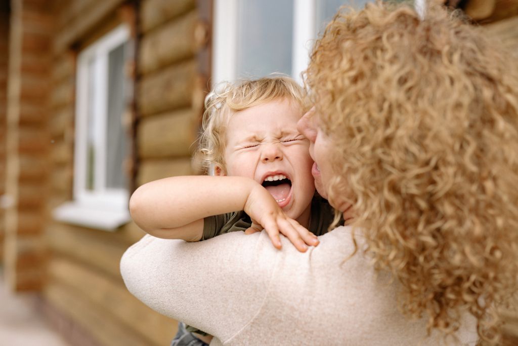 A joyful moment of a grandmother and grandson embracing and laughing outdoors.
